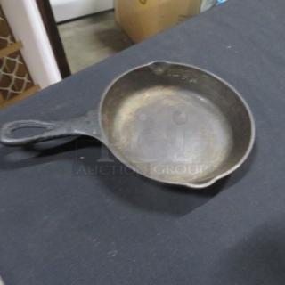 Lodge 6.5-inch cast iron skillet with visible wear; seasoned surface, ergonomic handle, dual pour spouts.