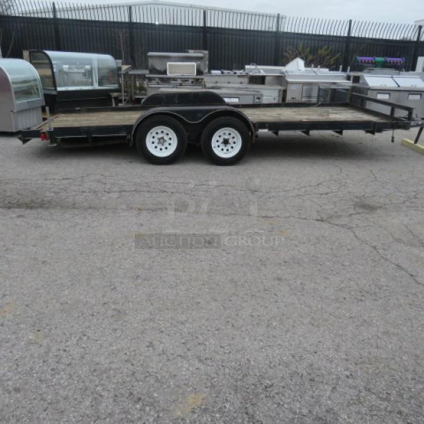 Ultra Tow 18-foot flatbed trailer, 5,000lb capacity, dual axles, white wheels. Appears in used condition.