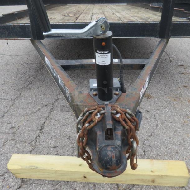 Ultra Tow 18 ft trailer, 5,000 lb capacity, visible wear, rust on frame, chains attached, labeled with brand markings.