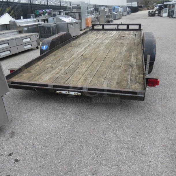 18-foot Ultra Tow trailer, 5,000lb capacity, wood plank bed, metal frame, fair condition, visible taillights and wheel fenders.