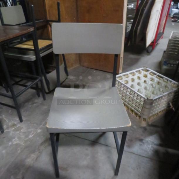 Gray wooden/metal chair with a solid seat and backrest, black metal frame, minimal wear. Suitable for dining or office use.