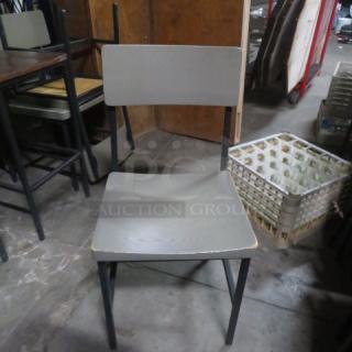 Gray wooden and metal chair, minimalist design, sturdy construction. Slight wear visible on edges, ideal for modern decor.