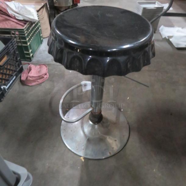 Chrome adjustable bar stool with black seat and scalloped edge. Features sturdy metal base. Used condition with some wear.