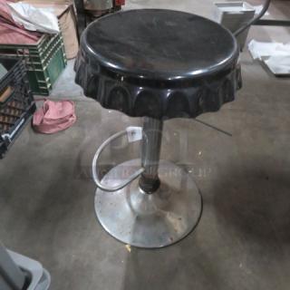 Chrome adjustable bar stool with black seat and scalloped edge. Features sturdy metal base. Used condition with some wear.
