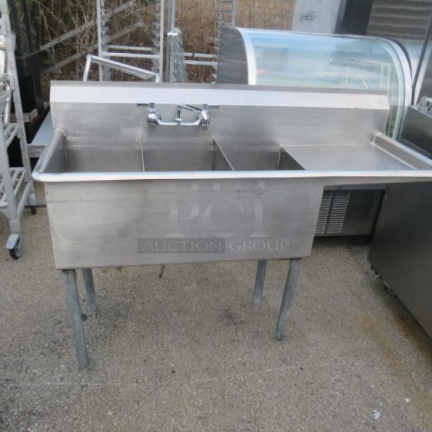 Stainless steel triple bowl sink with faucet and right-side drain board, 48x19x33 inches, in used condition.