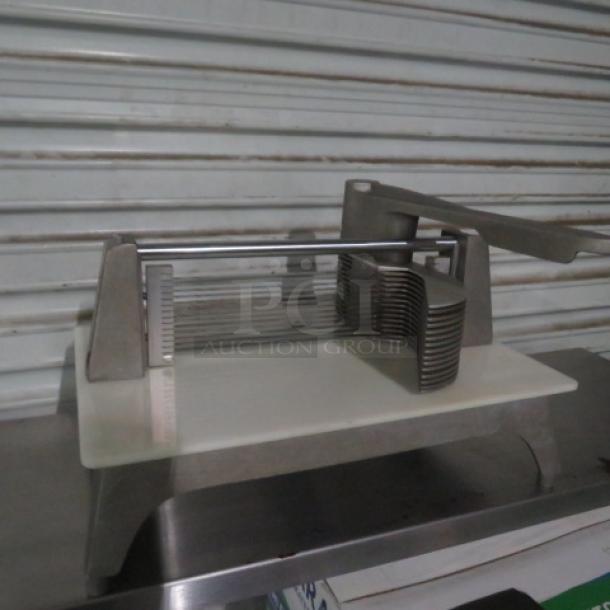 Commercial tomato slicer with stainless steel blades and a durable frame, in good condition, on a metal surface.