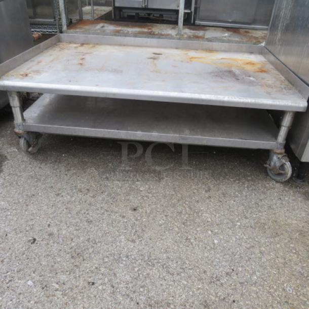 Stainless steel equipment table with under shelf on casters, 49x31x18 inches. Shows wear and rust on surface.