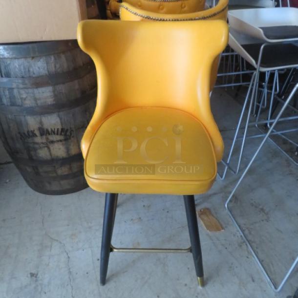 Vintage yellow bar stool with tufted back and footrest, in good condition. Features black legs with brass accents.