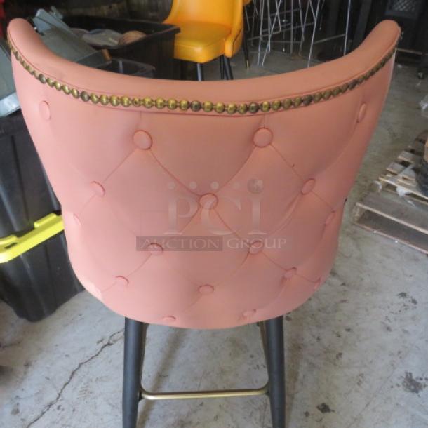 Vintage bar stool with tufted pink back and brass stud detailing. Features black legs and a gold footrest. Good condition.