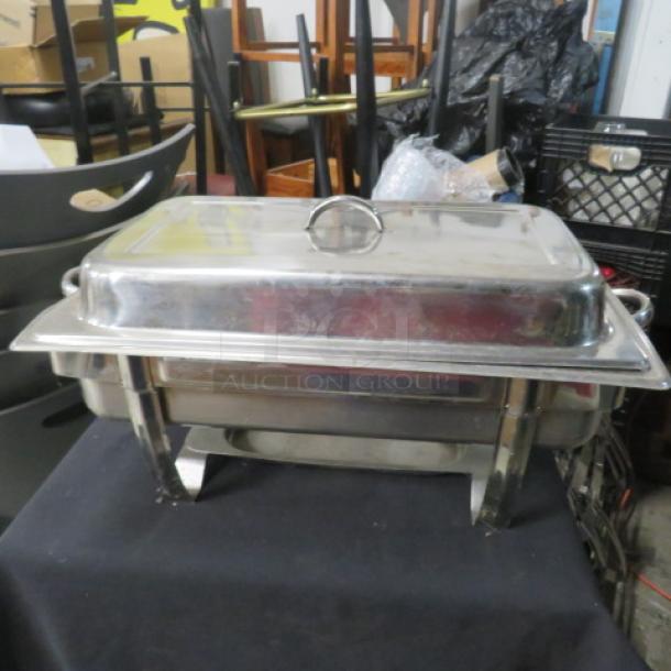Stainless steel full-size chafer with lid, features dual handles and sturdy legs. Appears in used condition.