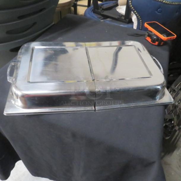 Stainless steel full-size hinged lid with handles, in good condition. Reflective surface with minor wear. Ideal for chafing dishes.