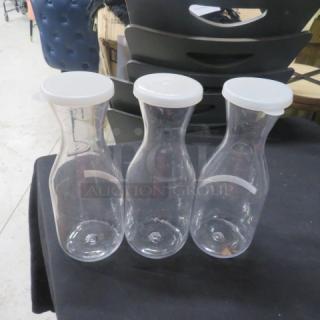 Set of three clear poly carafes with lids, model 3XBID. Each carafe features a sleek design, ideal for serving beverages.