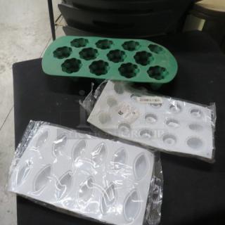 Assorted silicone baking molds, including green floral and two white designs, in new condition with packaging.