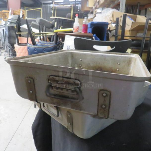 Aluminum roasting pan, 20.5x16.5x5 inches, sturdy handles, showing signs of wear, suitable for large-scale cooking.