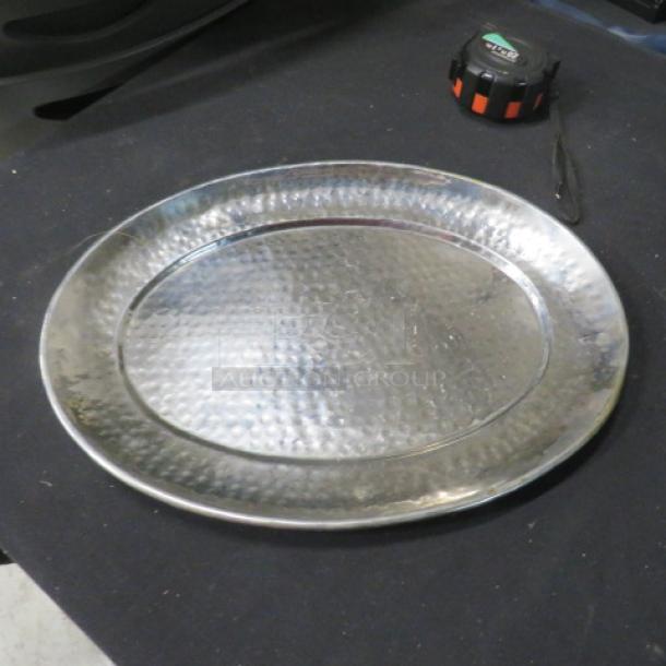 15x11.5 stainless steel hammered platter on black surface; shiny, textured finish, oval shape.