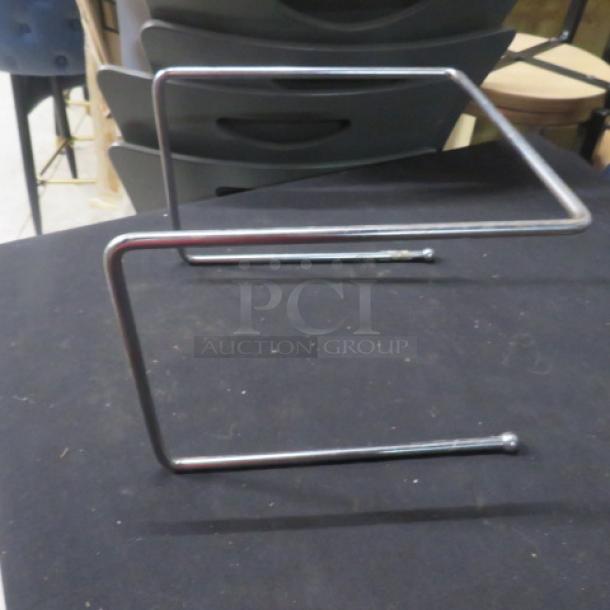 SS Pizza Stand, chrome finish, Z-shaped design, sturdy metal construction, used for elevating pizzas on tables.