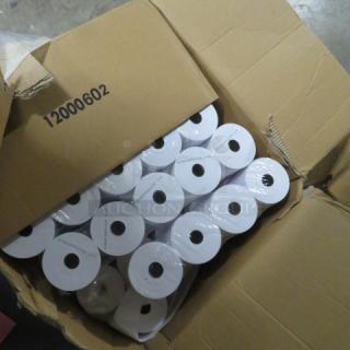 Case of white roll tape, unopened in a slightly damaged cardboard box labeled "12000602". Rolls tightly packed.