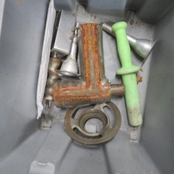 Lot of meat grinder accessories, including metal grinder part, discs, and green pusher; appears used, with some rust.