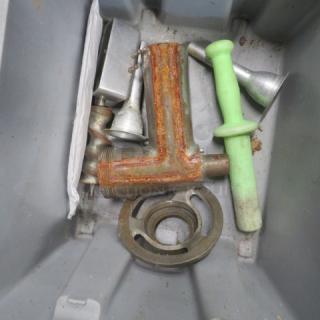 Lot of meat grinder accessories, including metal grinder part, discs, and green pusher; appears used, with some rust.