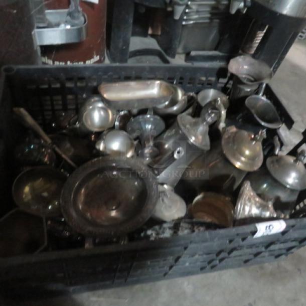 Assorted silver-plated serveware in a black crate, featuring various bowls, trays, and cups; appears tarnished.