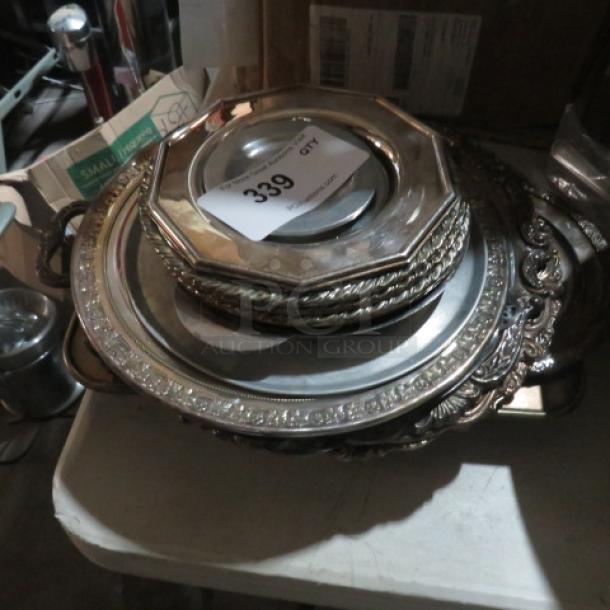 Assorted silver-plated serveware lot; includes trays and dishes with ornate patterns, in fair condition, auction tag visible.
