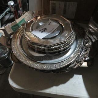 Assorted silver-plated serveware lot; includes trays and dishes with ornate patterns, in fair condition, auction tag visible.