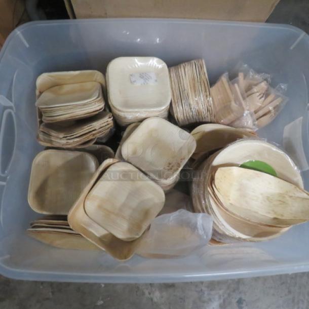 Plastic container filled with assorted bamboo plates, bowls, and utensils in various shapes and sizes, new condition.