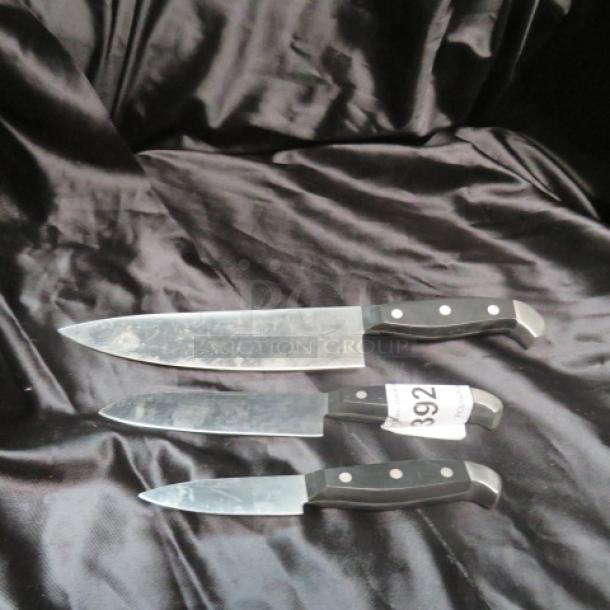 Assorted chef knife set with three knives on black fabric, displaying stainless steel blades and riveted handles. Tag labeled "392."