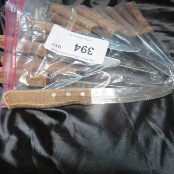 One lot of serrated steak knives with wooden handles in good condition, packaged in a clear ziplock bag, marked "394."