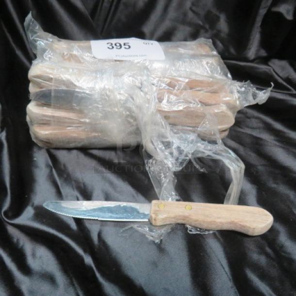 One lot of steak knives with wooden handles, partially wrapped in plastic. Item labeled with tag "395".