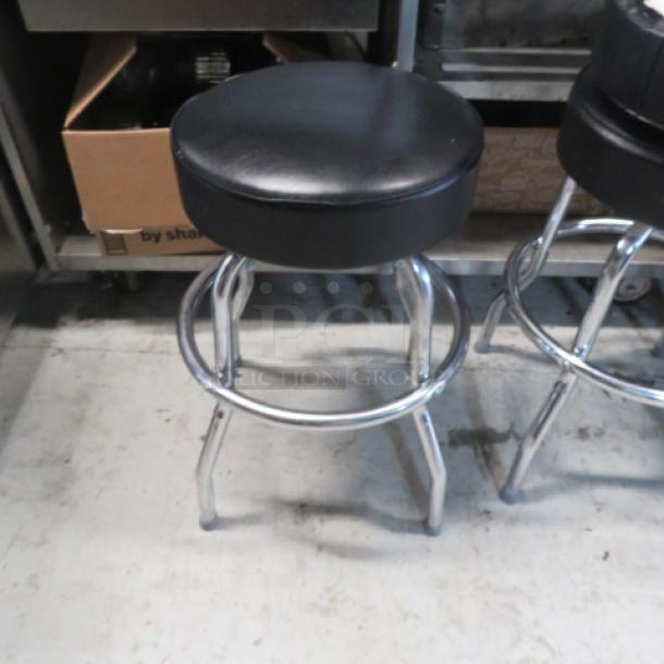Chrome ring stool with black cushioned seat, sturdy condition, featuring a sleek chrome finish and durable design.