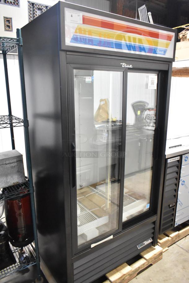 "Brand new True GDM-33-HC-LD 2-door cooler merchandiser with poly-coated racks, 115V, 1 phase, minor scratches visible."