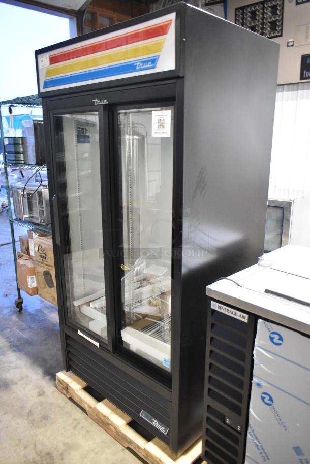 Brand new True GDM-33-HC-LD two-door cooler merchandiser with poly-coated racks; 115 volts, slight scratch, dent visible.