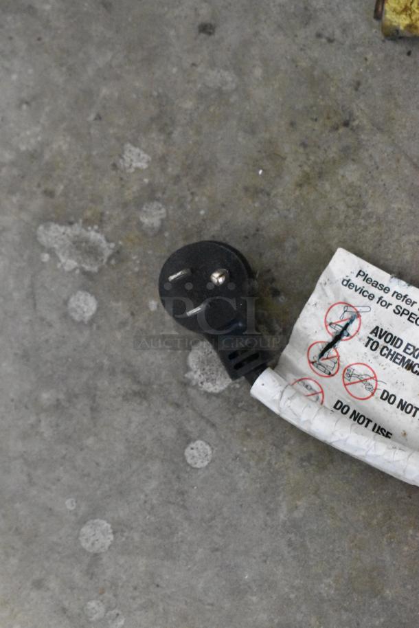 Metal vending machine power plug with a caution label, set on a concrete floor. 115 volts, 1 phase.