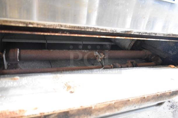 Bakers Pride stainless steel single deck pizza oven, showing interior with metal legs on commercial casters. Visible rust and wear.