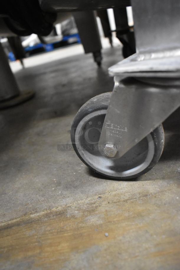 Metal commercial salad spinner on sturdy casters, close-up of wheel. Durable construction, ideal for high-volume use.