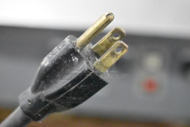 Close-up image of a Beseler heat sealer power plug, showing its prongs. Model: Commercial Countertop Heat Sealer, 115 Volts, 1 Phase.
