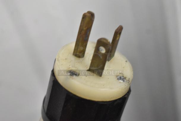 Close-up of a worn electrical plug with three metal prongs, associated with the Scotsman C0830SA-32B ice machine.