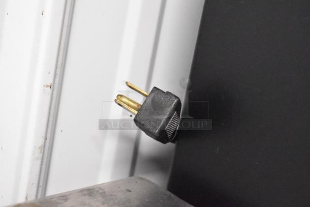 Three-prong electrical plug of the True GDM-12 cooler, 115 volts, for commercial use, showing safety and compatibility.