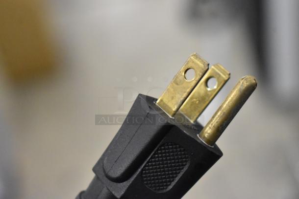 Close-up of a three-prong electrical plug for the True GDM-12-HC-LD cooler, showing gold-colored prongs on a black base.