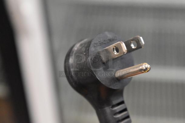 Close-up view of an electrical plug for the 2021 True TSCI-600R-G-PH commercial cooler, showing plug prongs and a portion of the cord.
