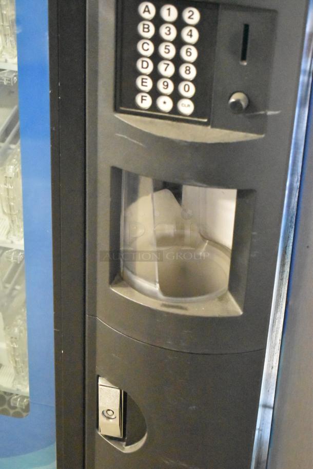 Metal commercial bottled drink vending machine, keypad and coin slot visible. Operates at 115 volts, 1 phase. Good condition.