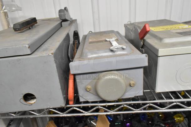 Five various used power boxes with visible handles and connectors, featuring different designs and red lever.