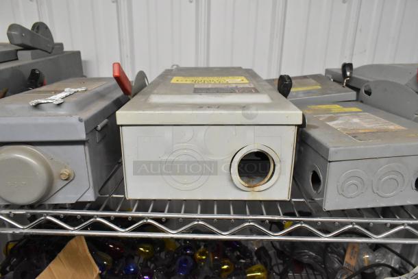 Five various power boxes on a metal shelf, featuring multiple outlets and switches. Labels show signs of wear. 