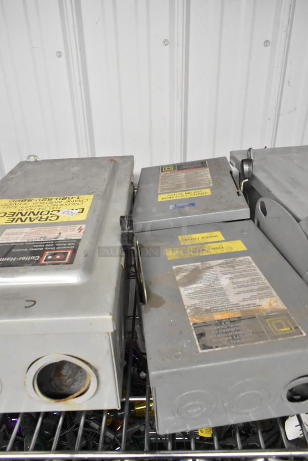 Five various power boxes on a metal shelf. Labels indicate use for cranes. Some rust and wear visible.