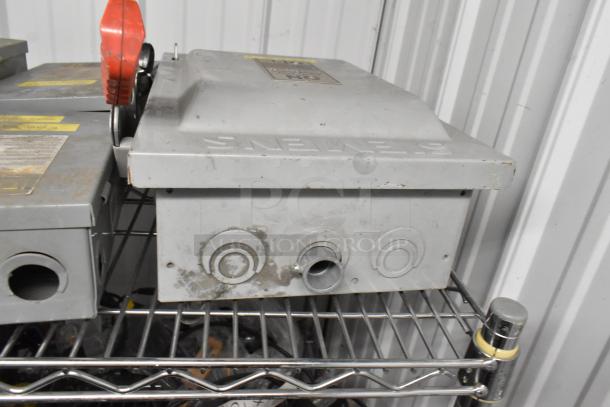 Five Siemens power boxes on a metal shelf, featuring conduit openings and visible surface wear, ready for auction.