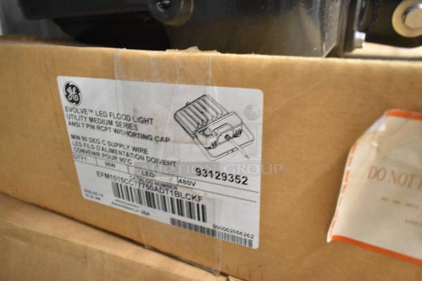 Four GE Evolve LED flood lights, utility medium series, model EFM1015C7, new in box with label showing specifications.