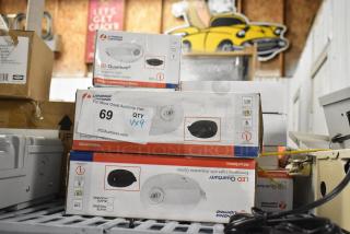 Stack of Lithonia Lighting emergency lights and exit signs in boxes, labeled "LED Quantum." Auction tag shows quantity "9."
