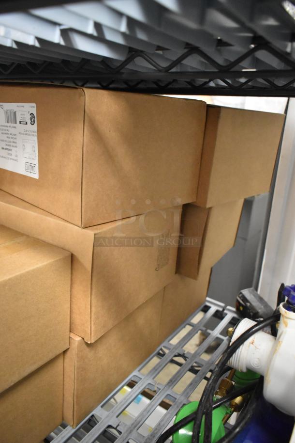 6 new Dual Lite EVHC6IDP-WM LED emergency lights in sealed boxes, stacked on a shelf. Labels confirm model and condition.