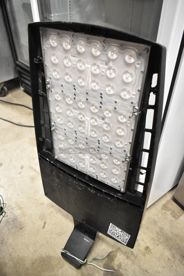 LED flood light fixture, black casing, multiple white bulbs, integrated mounting base. QR code visible on bottom panel.